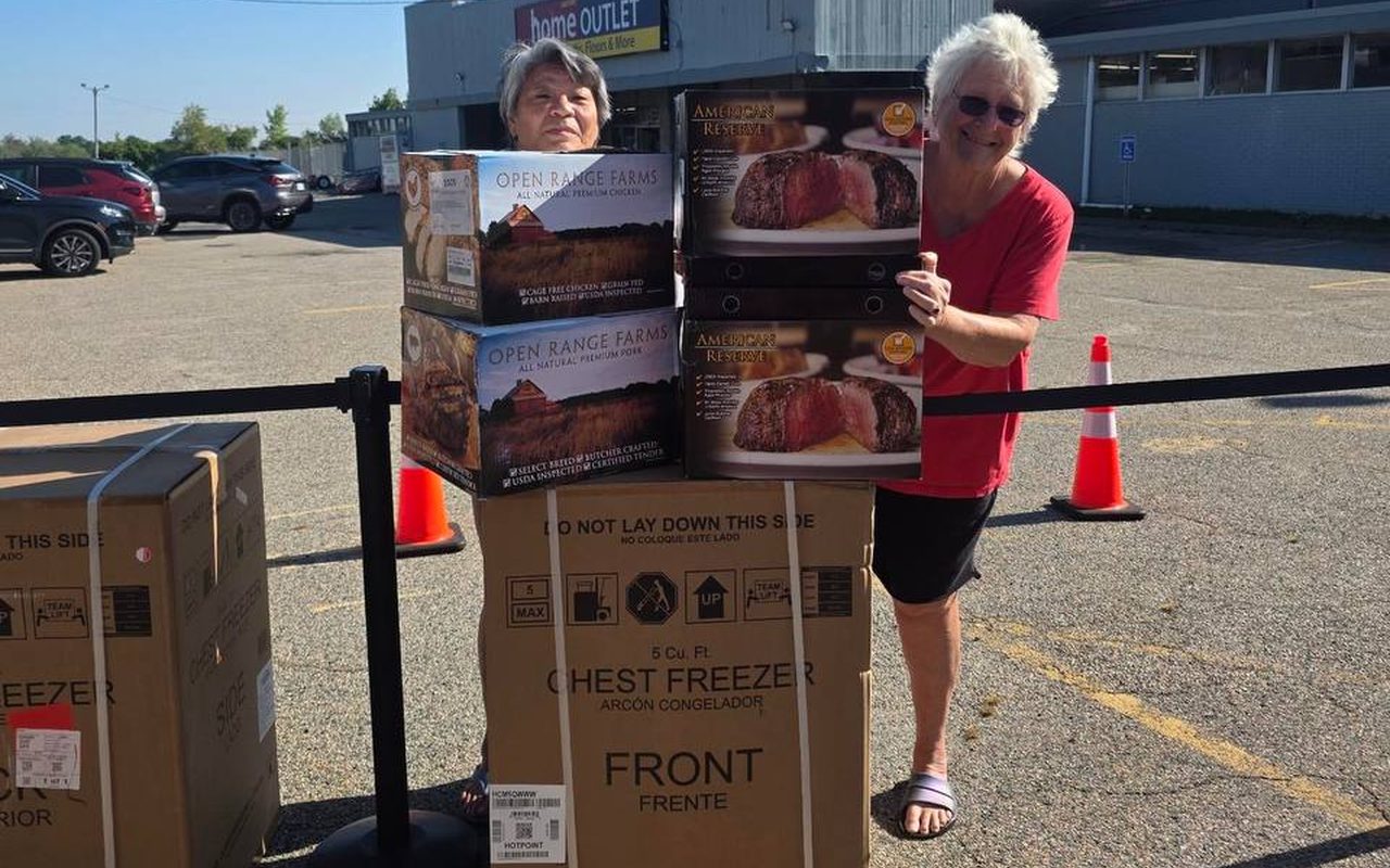 Two customers holding boxes of steak and chicken