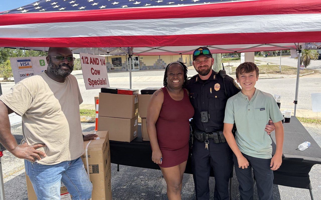 A family and a local police officer with the crew under the flag tent
